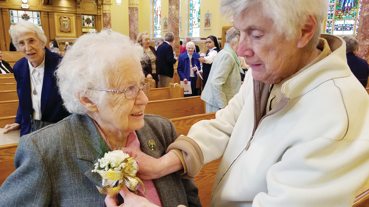 Before Mass, sisters help one another with their corsages in celebration of their many years of service.